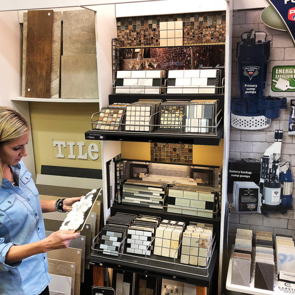 Woman examining tile samples in store.