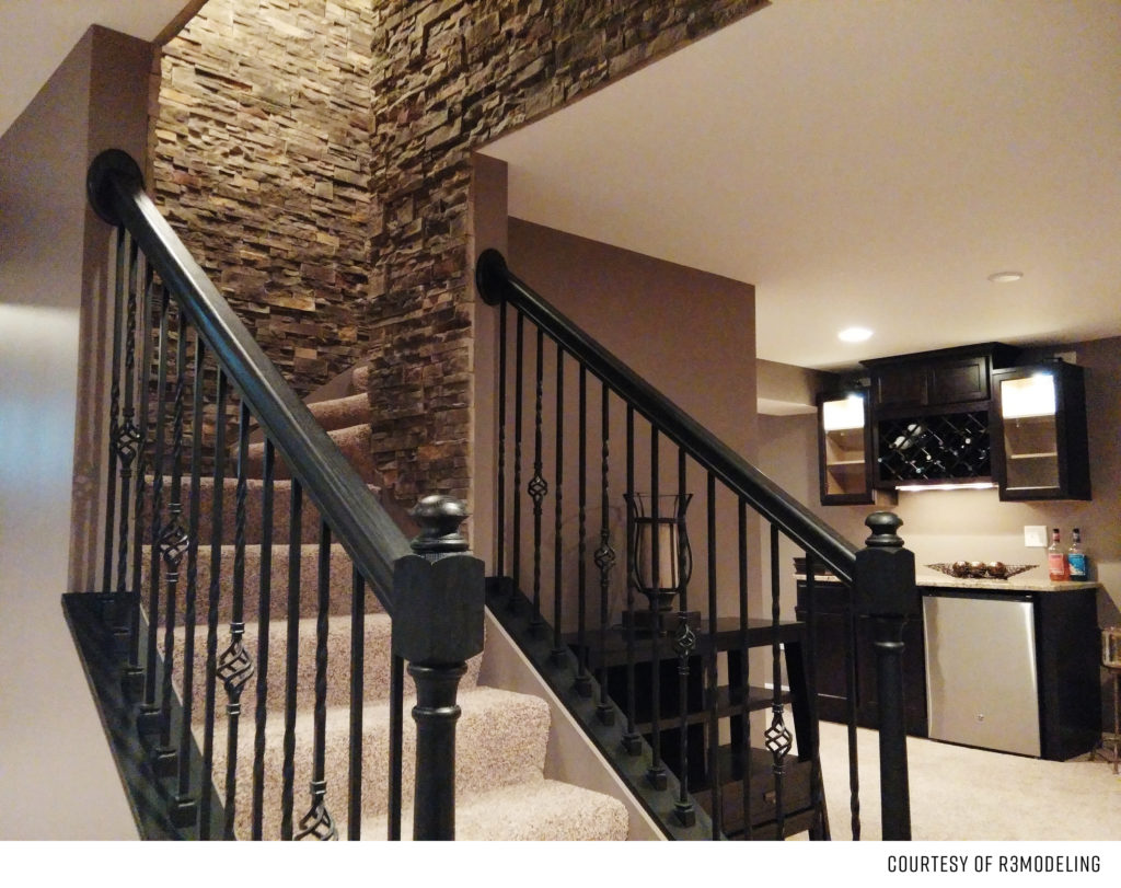 Modern staircase with black metal railings and stone accent wall.