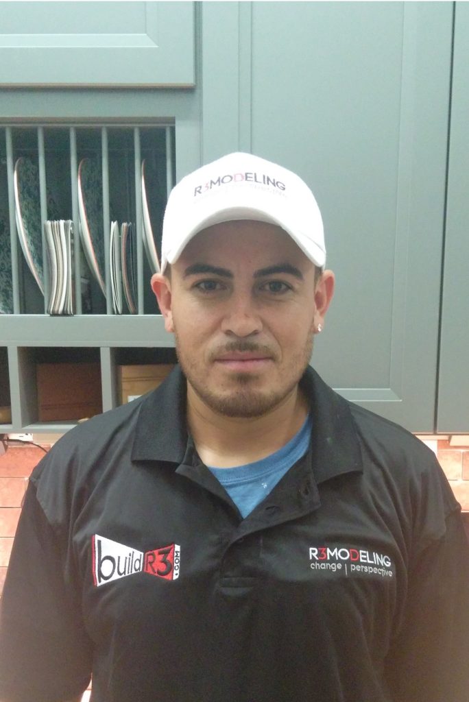 Man wearing a white cap and a black vest stands indoors.