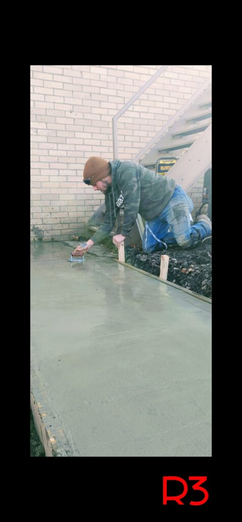 Man smoothing freshly poured concrete surface.