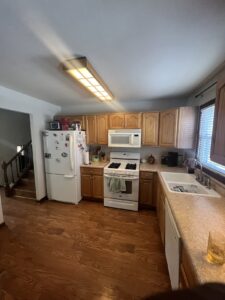 Wooden kitchen with appliances and white cabinets.