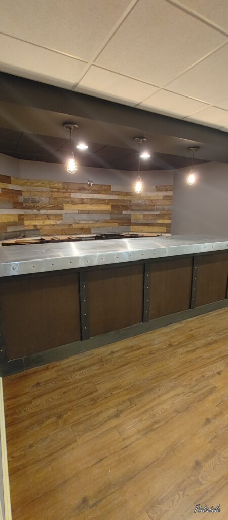 Empty bar counter with wooden paneling and overhead lights.