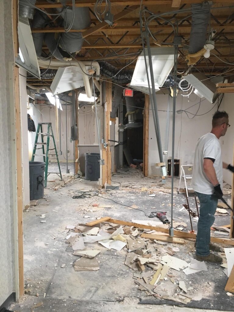 Room undergoing extensive demolition with debris and exposed walls.