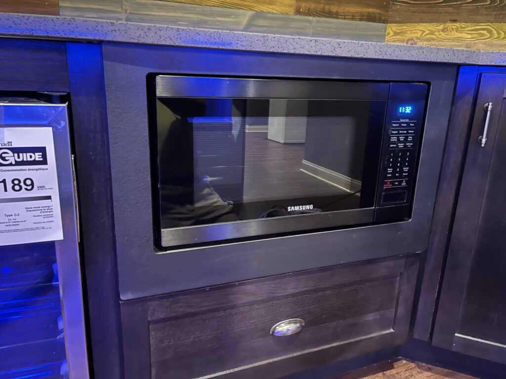 Built-in microwave oven installed in dark wooden cabinetry with digital controls.